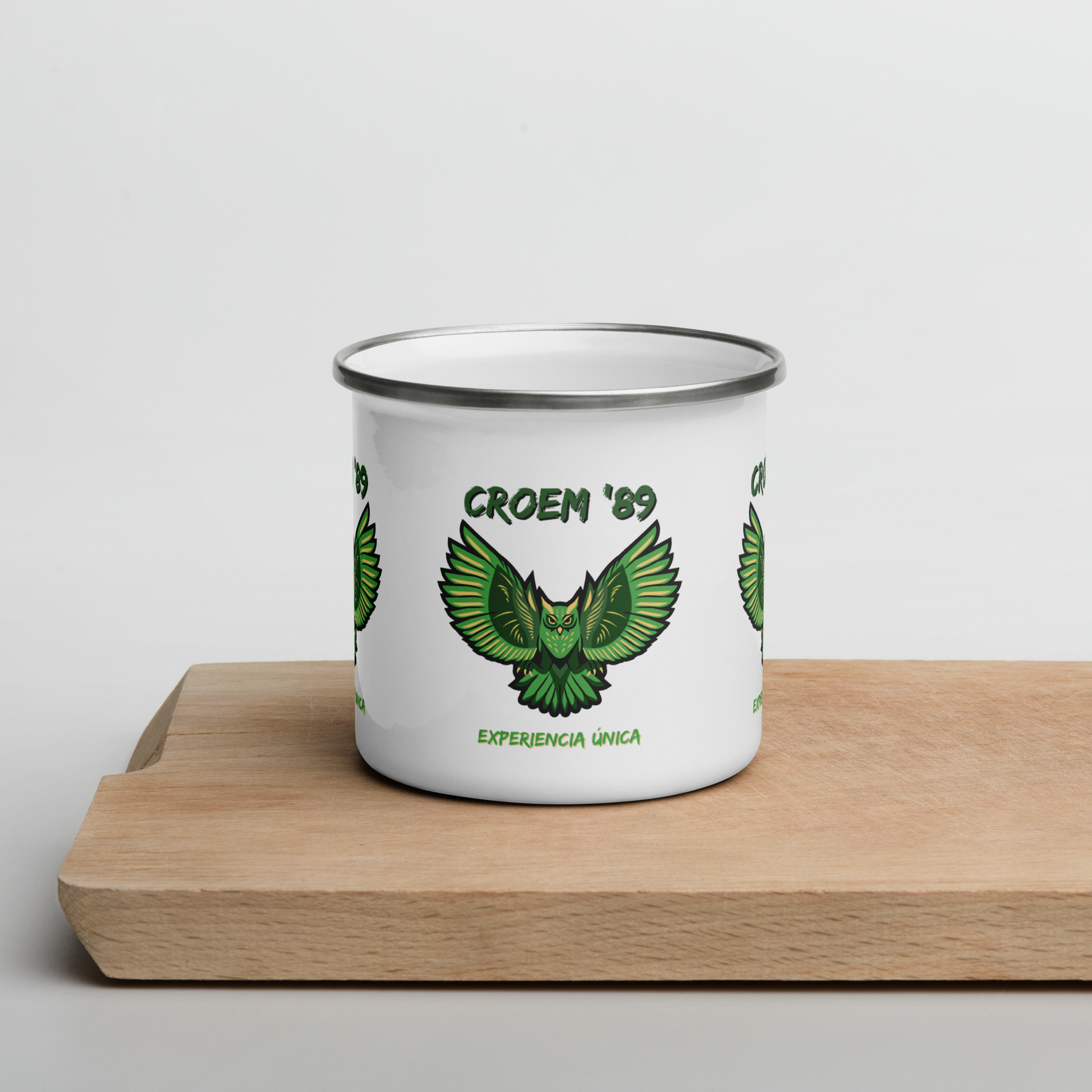 Image of a white metal mug with a green stylized owl and the words "CROAM '89" and "Experience única".